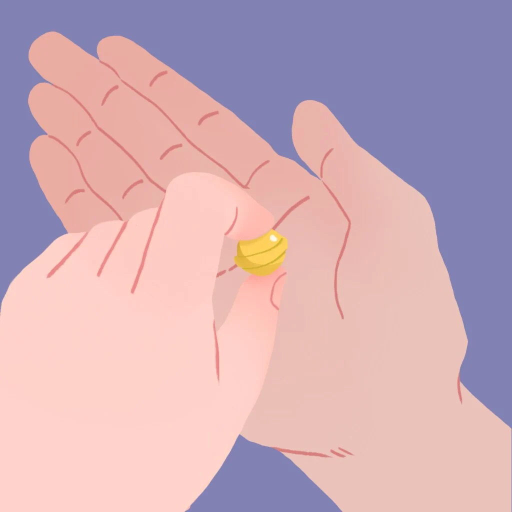 Deux mains roulant doucement une petite perle jaune entre leurs doigts sur un fond bleu