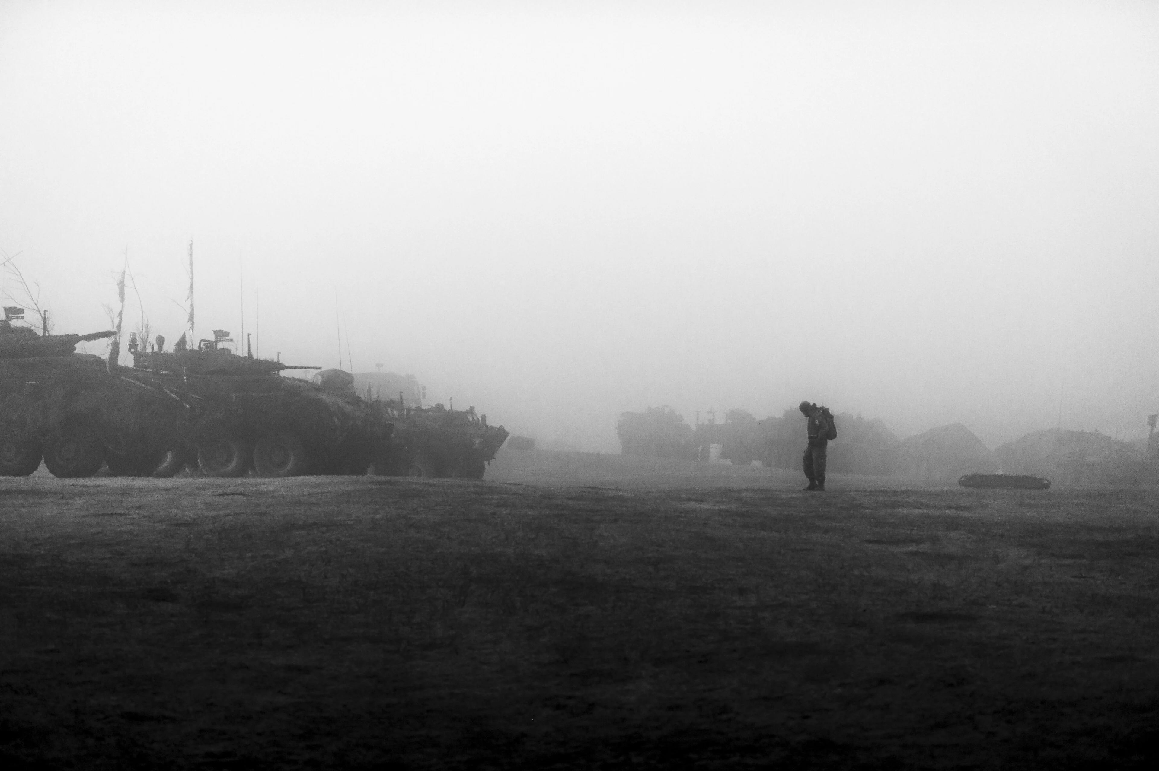 Canadian Armed Forces armoured vehicles and a soldier in dense fog.