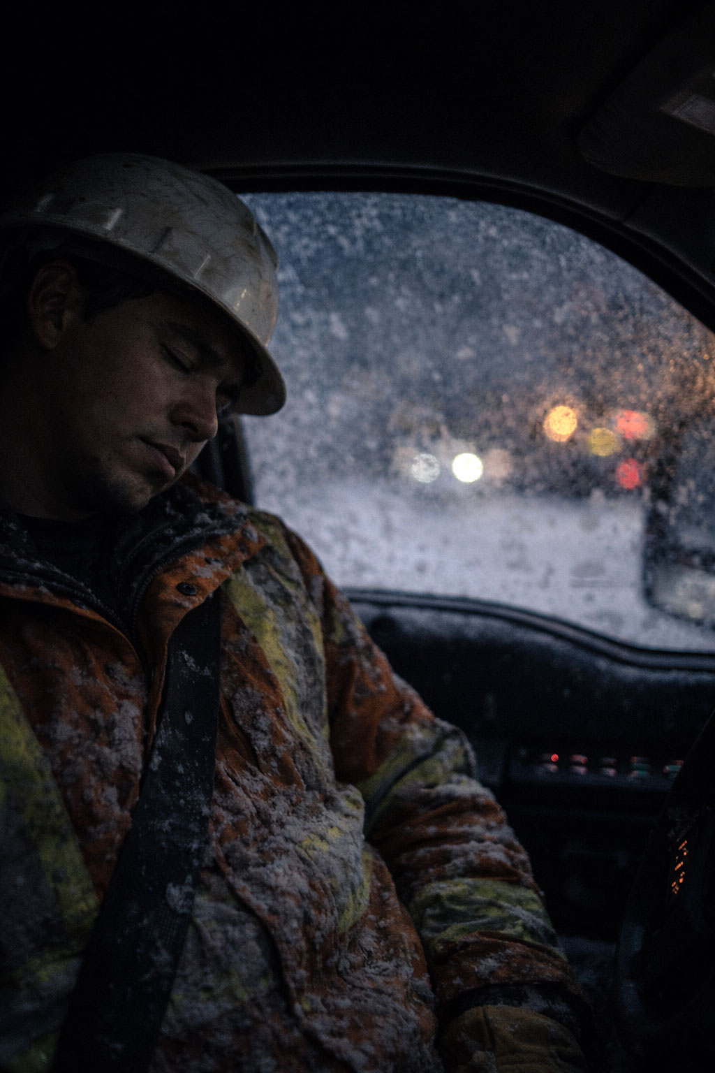 A exhausted power line technician sleeps in his truck at the end of a gruelling shift